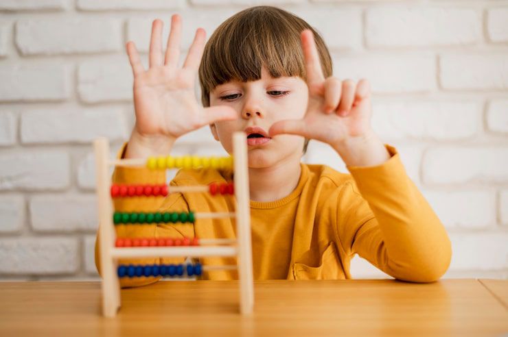 child in a yellow shirt using an abacus and counting on their fingers